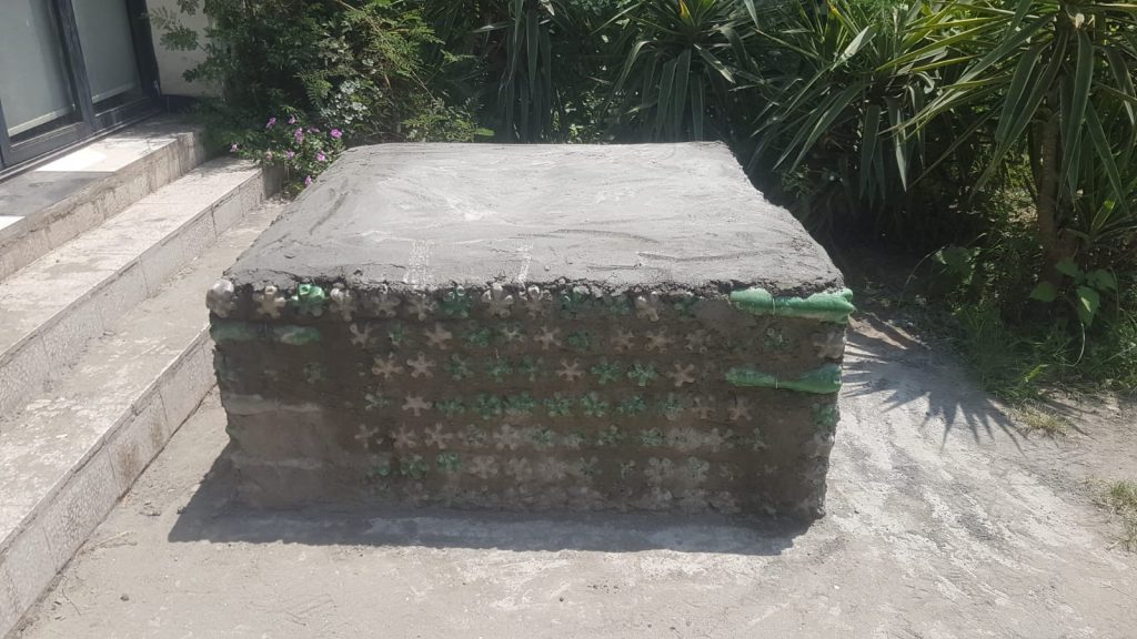 A low block of stacked bottle bricks finished with a cement top.