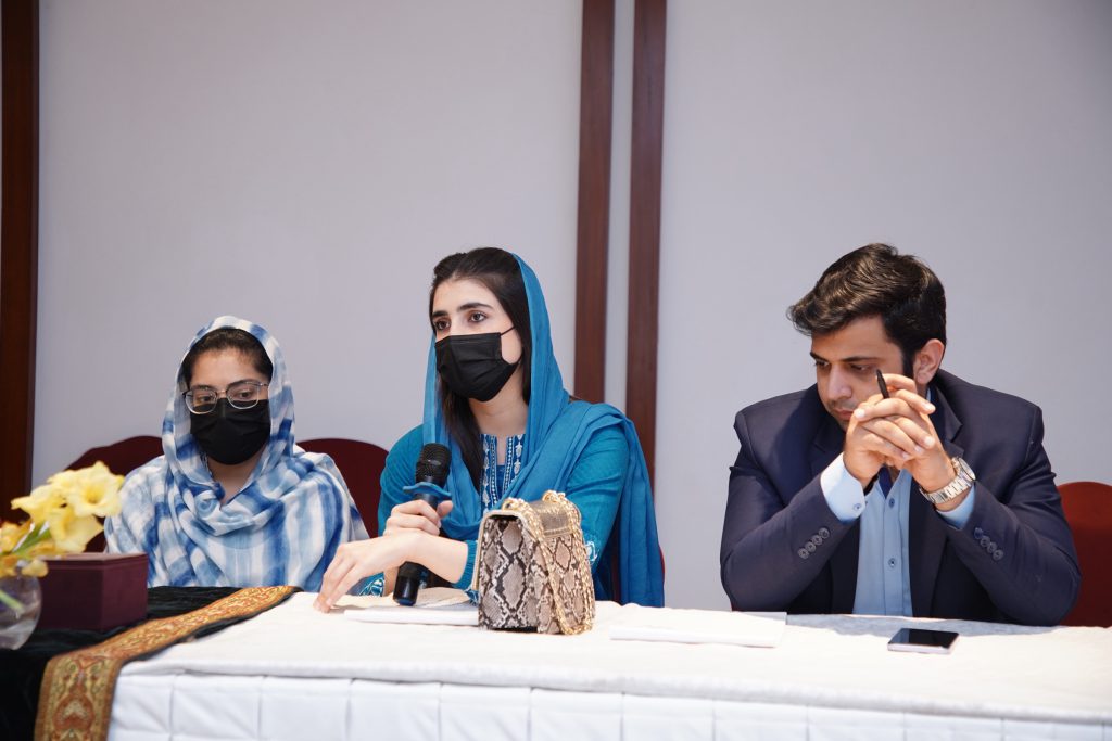 Workshop participants seated at a conference table, one speaking into a microphone.